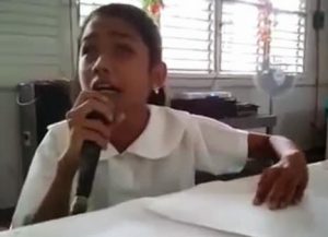 Joyce Jimenez, a blind girl from the Philippines holding a mic in one hand and Braille in another